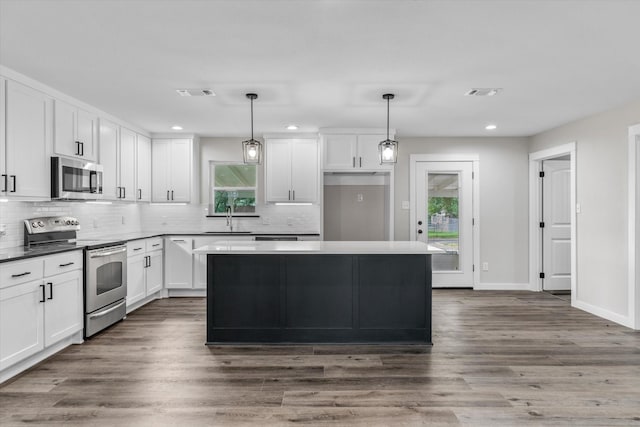 kitchen with pendant lighting, sink, white cabinets, and appliances with stainless steel finishes