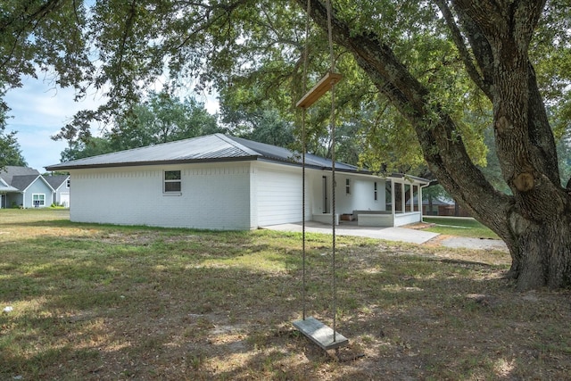 back of house featuring a yard, a sunroom, and a patio area