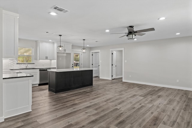 kitchen with a kitchen island, pendant lighting, white cabinetry, dishwasher, and decorative backsplash