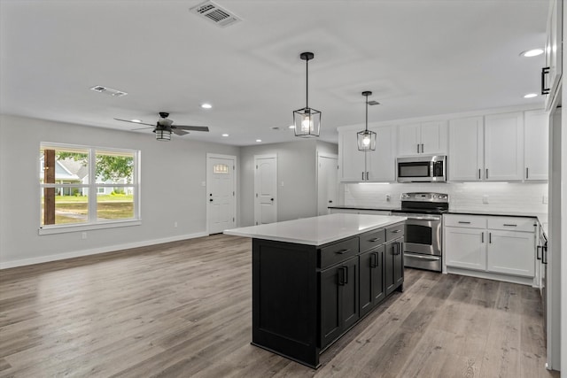 kitchen with hanging light fixtures, backsplash, stainless steel appliances, a center island, and white cabinets