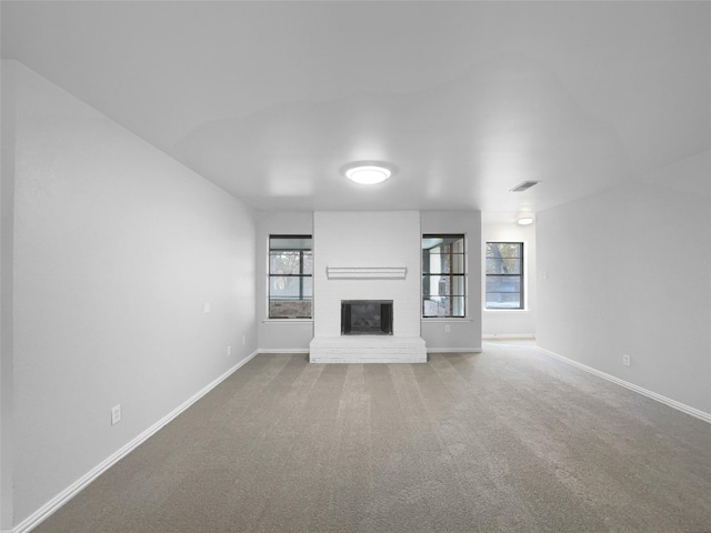 unfurnished living room with carpet flooring and a brick fireplace