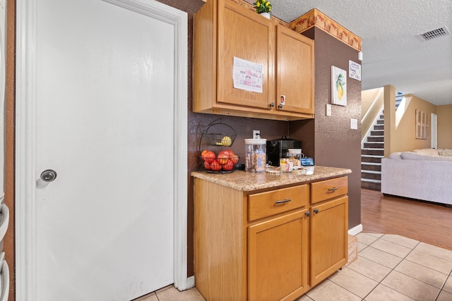 kitchen featuring a textured ceiling, light countertops, light tile patterned flooring, and visible vents