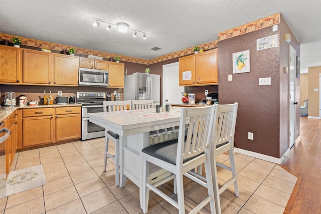 kitchen featuring stainless steel appliances, visible vents, a textured ceiling, and light tile patterned floors