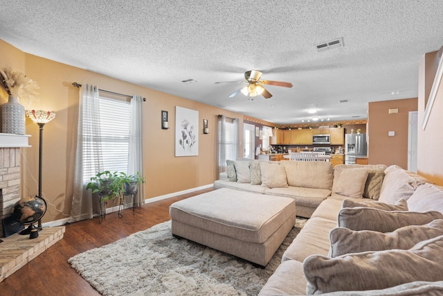 living area featuring a textured ceiling, a wealth of natural light, dark wood-style flooring, and visible vents