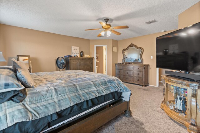 carpeted bedroom featuring a ceiling fan, visible vents, a textured ceiling, and baseboards