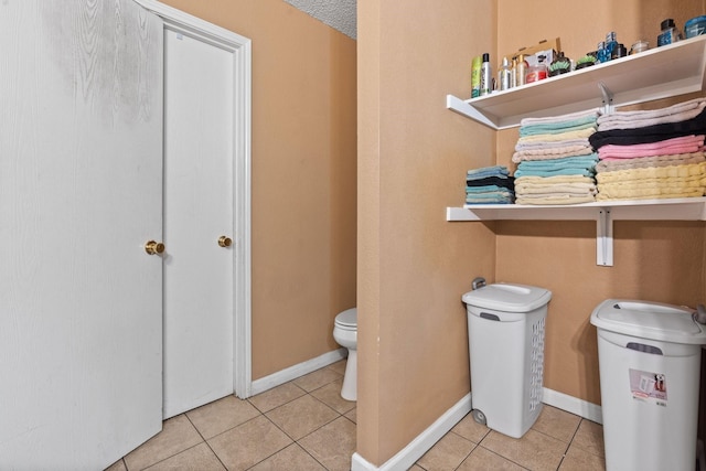 bathroom with baseboards, toilet, and tile patterned floors