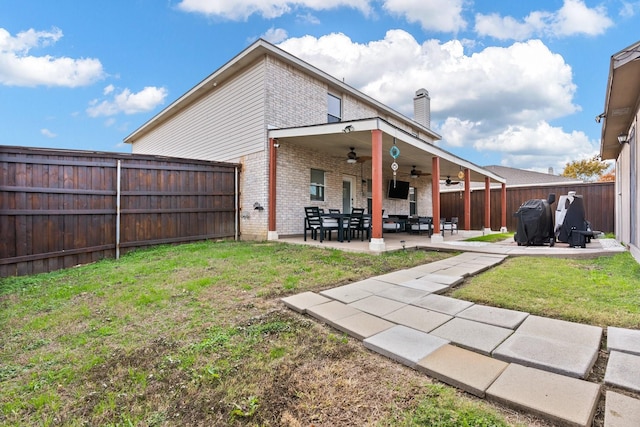 back of property featuring ceiling fan, a fenced backyard, brick siding, a yard, and a patio area