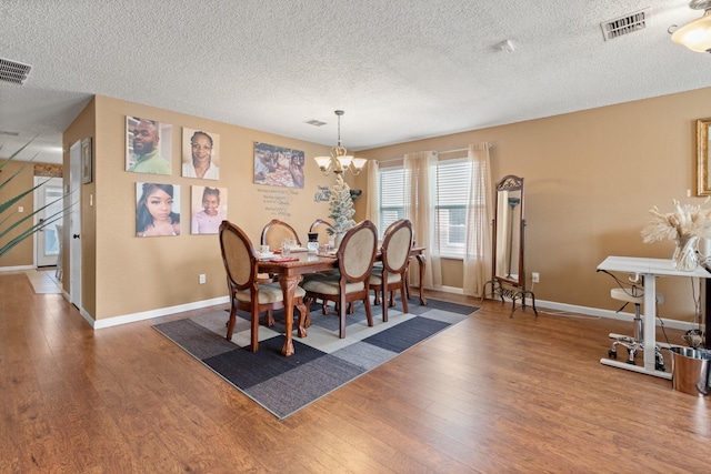 dining area with a chandelier, visible vents, baseboards, and hardwood / wood-style flooring