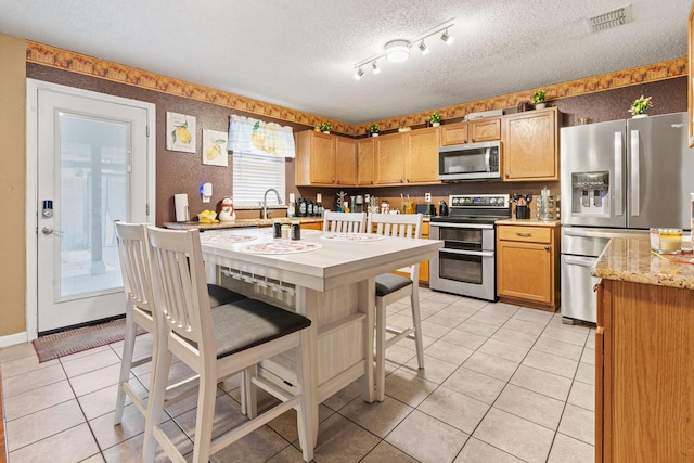 kitchen featuring light tile patterned floors, visible vents, baseboards, appliances with stainless steel finishes, and a textured ceiling