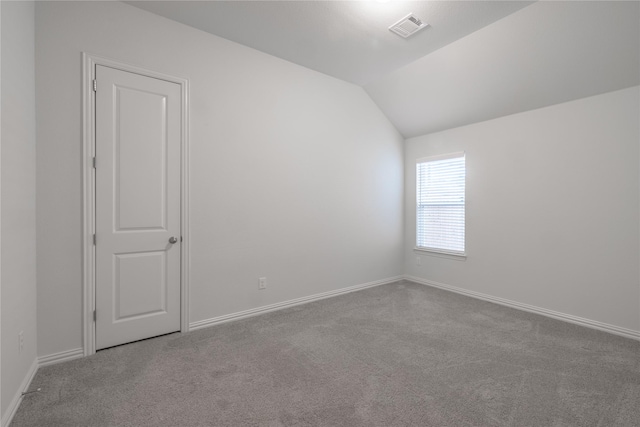 carpeted spare room featuring vaulted ceiling