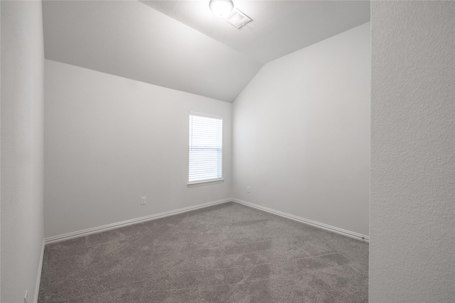 carpeted empty room featuring vaulted ceiling