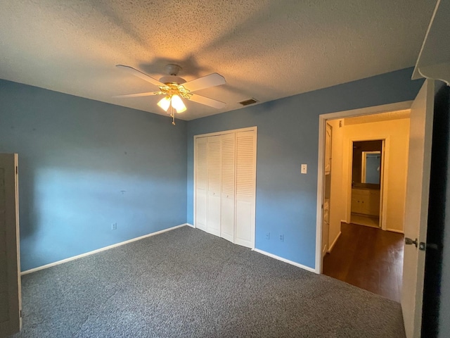 unfurnished bedroom featuring ceiling fan, a closet, dark carpet, and a textured ceiling