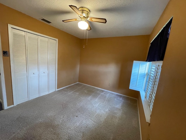 unfurnished bedroom featuring carpet, a textured ceiling, a closet, and ceiling fan