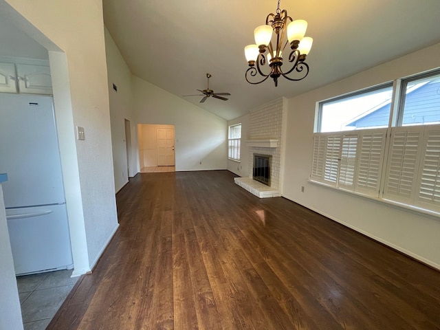 unfurnished living room featuring a fireplace, ceiling fan with notable chandelier, dark hardwood / wood-style floors, and vaulted ceiling