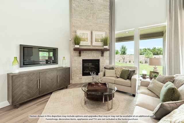 living room featuring a large fireplace, a towering ceiling, and light hardwood / wood-style flooring