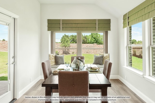 dining space with light hardwood / wood-style floors, lofted ceiling, and a wealth of natural light