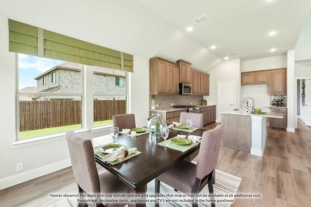 dining room with light hardwood / wood-style flooring and lofted ceiling