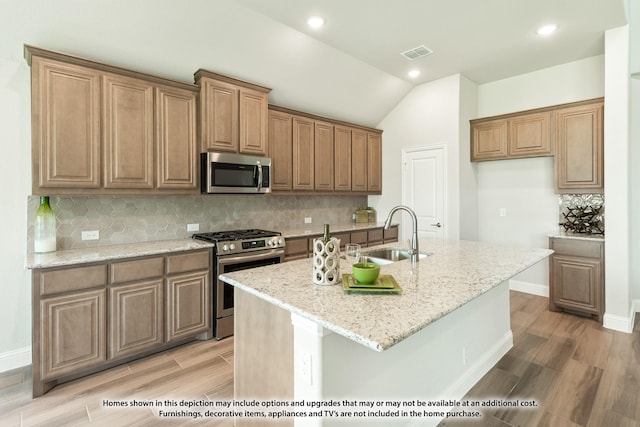 kitchen featuring a center island with sink, sink, lofted ceiling, and stainless steel appliances