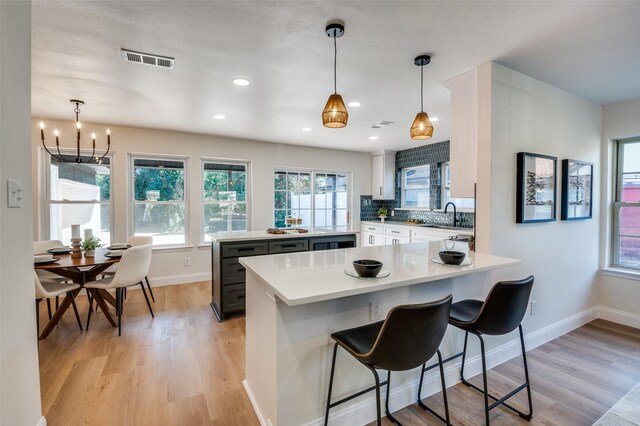 kitchen featuring hanging light fixtures, stainless steel appliances, a center island, and white cabinets