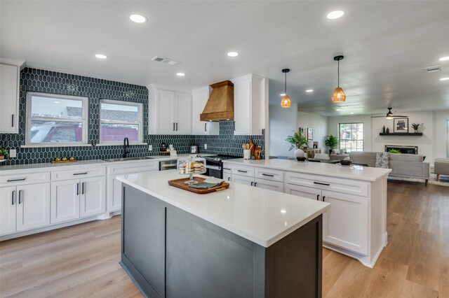 dining area with ceiling fan, sink, a fireplace, and light hardwood / wood-style flooring