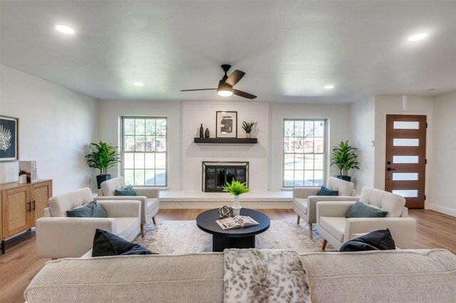 living room with a brick fireplace, light hardwood / wood-style floors, and a healthy amount of sunlight