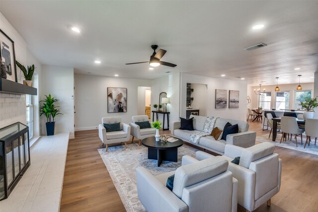 living room featuring ceiling fan, light wood-type flooring, and a fireplace