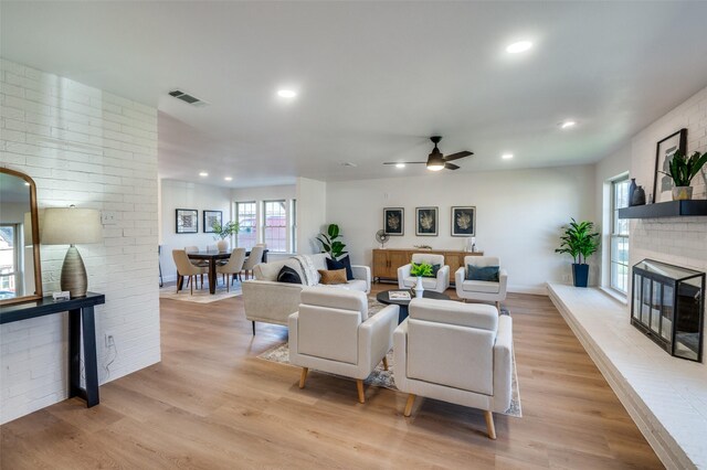 living room featuring a brick fireplace, hardwood / wood-style floors, and ceiling fan