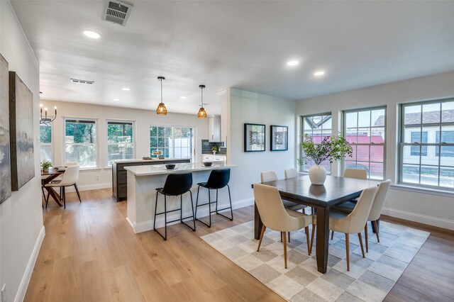 dining space featuring a chandelier, wet bar, beverage cooler, and light wood-type flooring