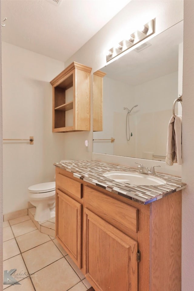 bathroom with tile patterned floors, vanity, toilet, and walk in shower