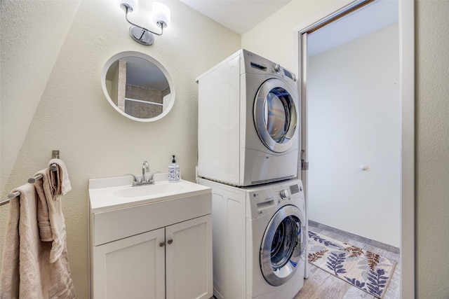 laundry room with sink, cabinets, and stacked washer / dryer