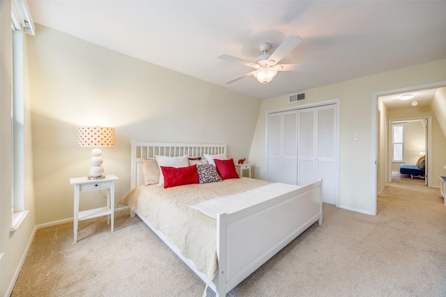 bedroom featuring light colored carpet, a closet, and ceiling fan