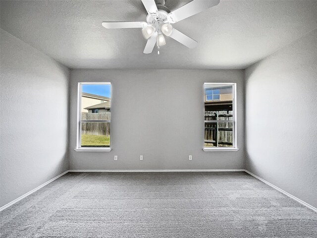 carpeted empty room with ceiling fan and a textured ceiling