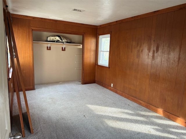 unfurnished bedroom featuring wood walls, a closet, and carpet floors