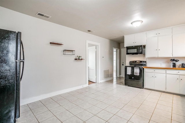 kitchen featuring light tile patterned flooring, white cabinets, and black appliances