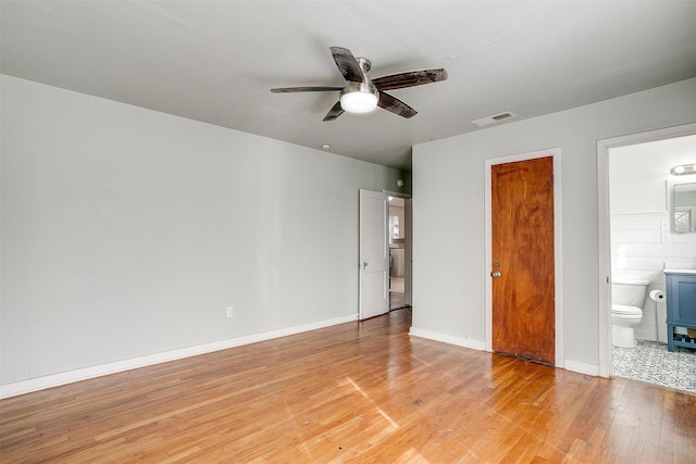 unfurnished bedroom with ceiling fan, wood-type flooring, and connected bathroom