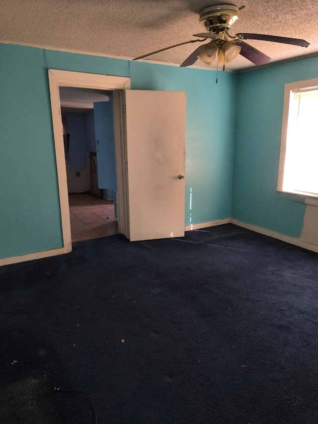 carpeted empty room with ceiling fan and a textured ceiling