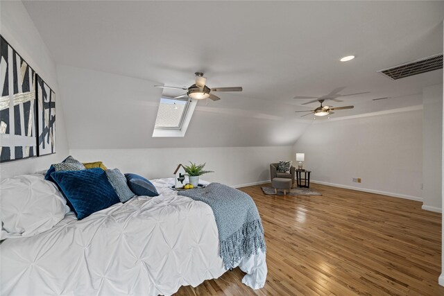 bedroom with hardwood / wood-style flooring, lofted ceiling with skylight, and ceiling fan