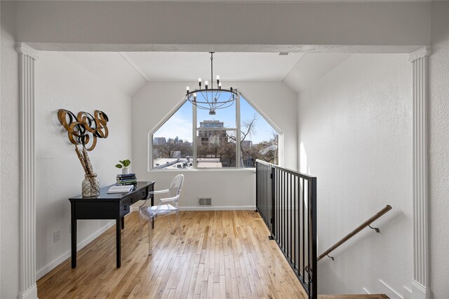 interior space featuring a chandelier, light hardwood / wood-style floors, and vaulted ceiling