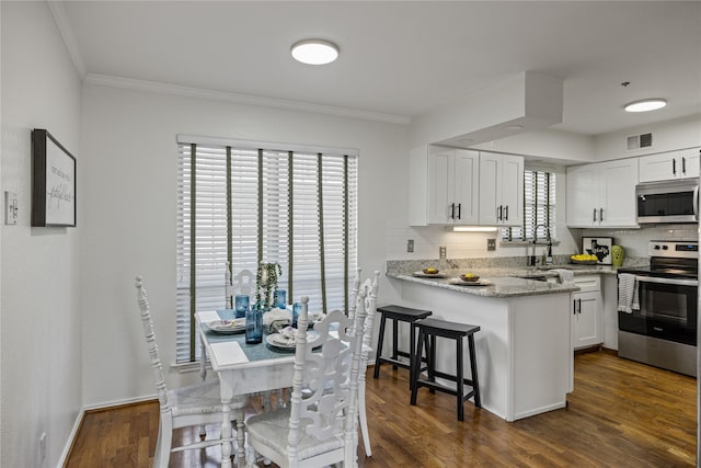 kitchen featuring kitchen peninsula, dark hardwood / wood-style flooring, white cabinetry, and stainless steel appliances