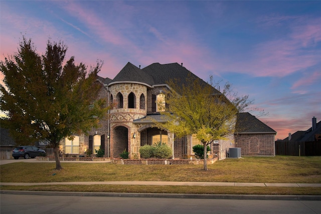 french provincial home with a lawn and central AC unit