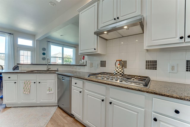 kitchen featuring dark stone counters, white cabinets, sink, light wood-type flooring, and appliances with stainless steel finishes