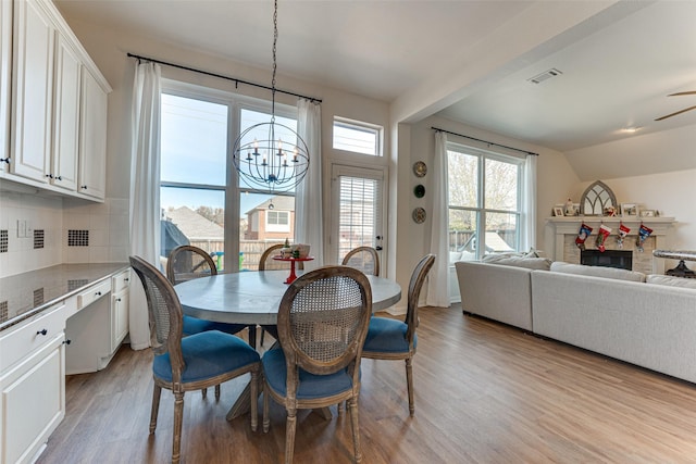 dining area with ceiling fan with notable chandelier and light hardwood / wood-style floors