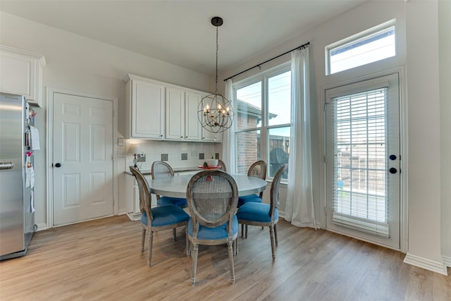 dining area with light hardwood / wood-style flooring and a notable chandelier