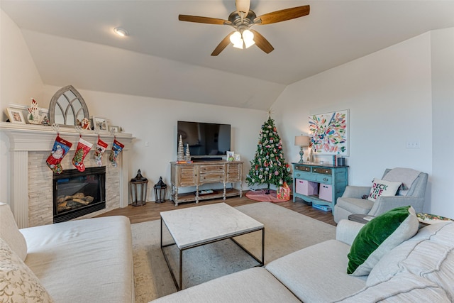 living room with a stone fireplace, ceiling fan, hardwood / wood-style floors, and vaulted ceiling