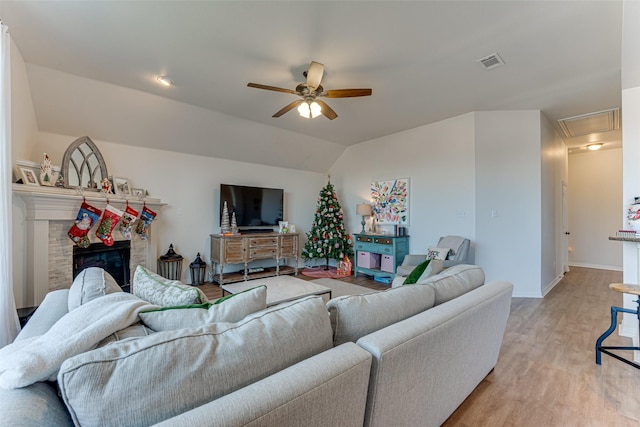 living room with ceiling fan, a fireplace, light hardwood / wood-style floors, and lofted ceiling