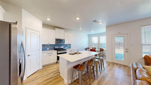 kitchen featuring sink, a breakfast bar area, white cabinetry, a center island with sink, and appliances with stainless steel finishes