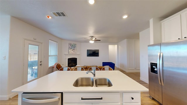 kitchen featuring sink, white cabinetry, light wood-type flooring, appliances with stainless steel finishes, and an island with sink