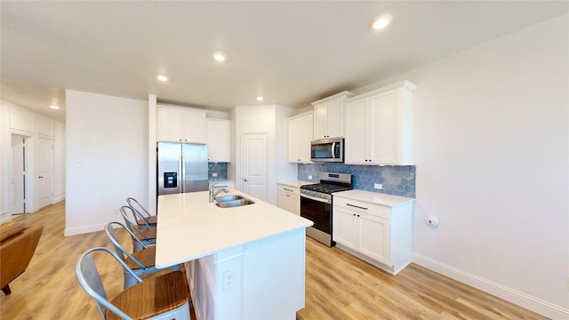 kitchen featuring white cabinetry, sink, a breakfast bar area, a kitchen island with sink, and stainless steel appliances