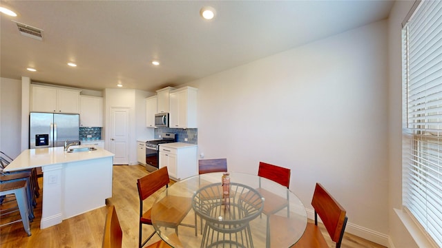 dining space with a wealth of natural light, sink, and light wood-type flooring