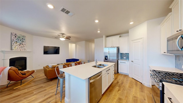 kitchen featuring stainless steel appliances, white cabinetry, sink, and a center island with sink